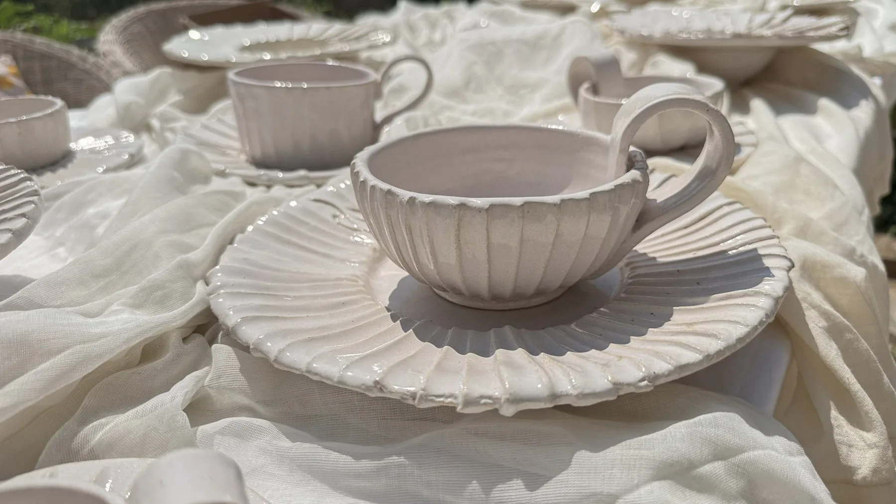 Handcrafted ivory ceramic cup and plate on a softly draped table