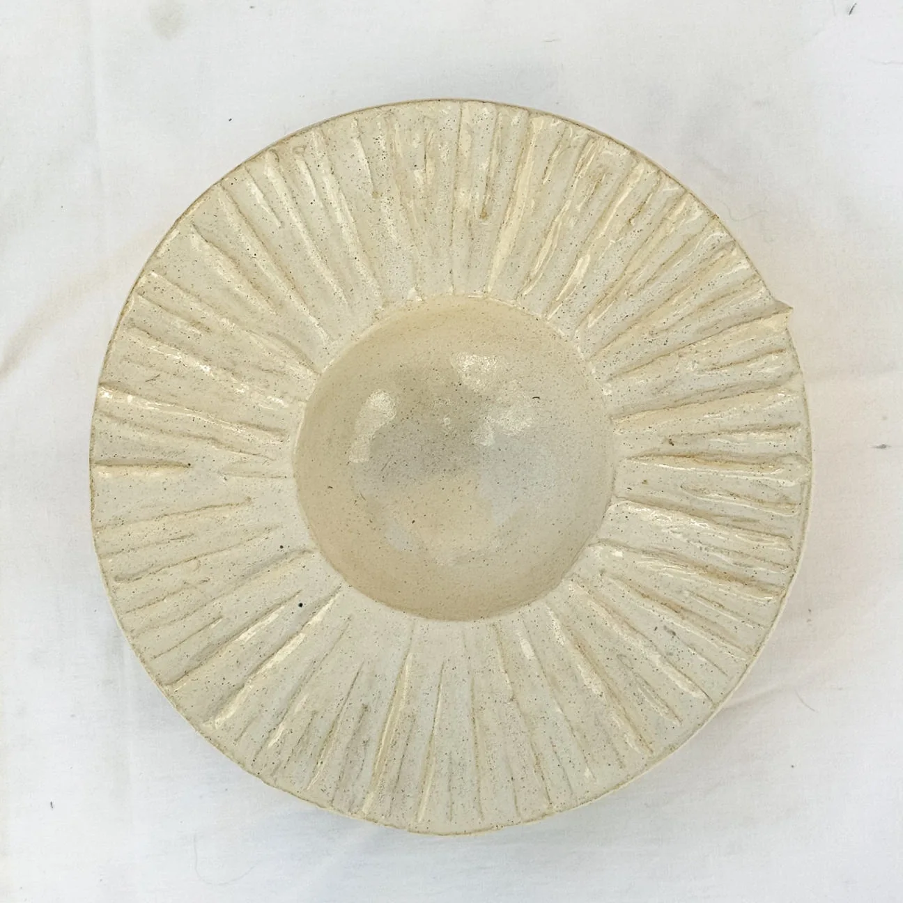 Piega ceramic plate with compressed pleats
