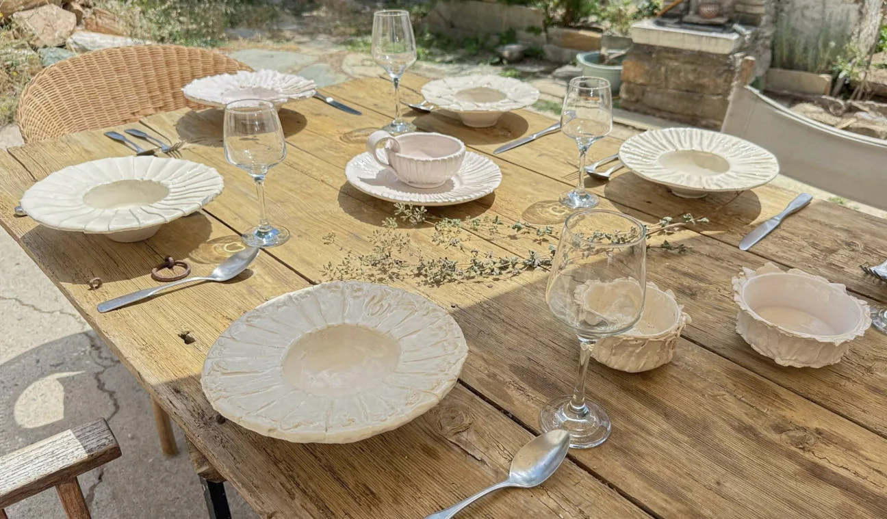 Ceramic plates and cups laid out on a sunlit table